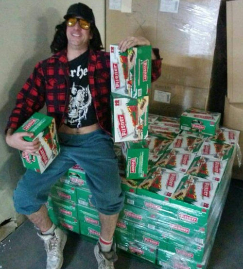Stacked green snack boxes with Pils labels, held and piled beside the person